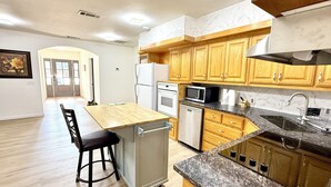 A kitchen with wooden cabinets, a stainless steel sink, and a built-in microwave.