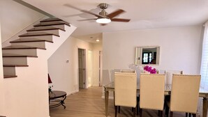 A dining area with a table and chairs, a staircase, and a ceiling fan.