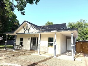 Une maison de plain-pied avec un porche couvert, une porte d’entrée et un petit jardin à l’avant.
