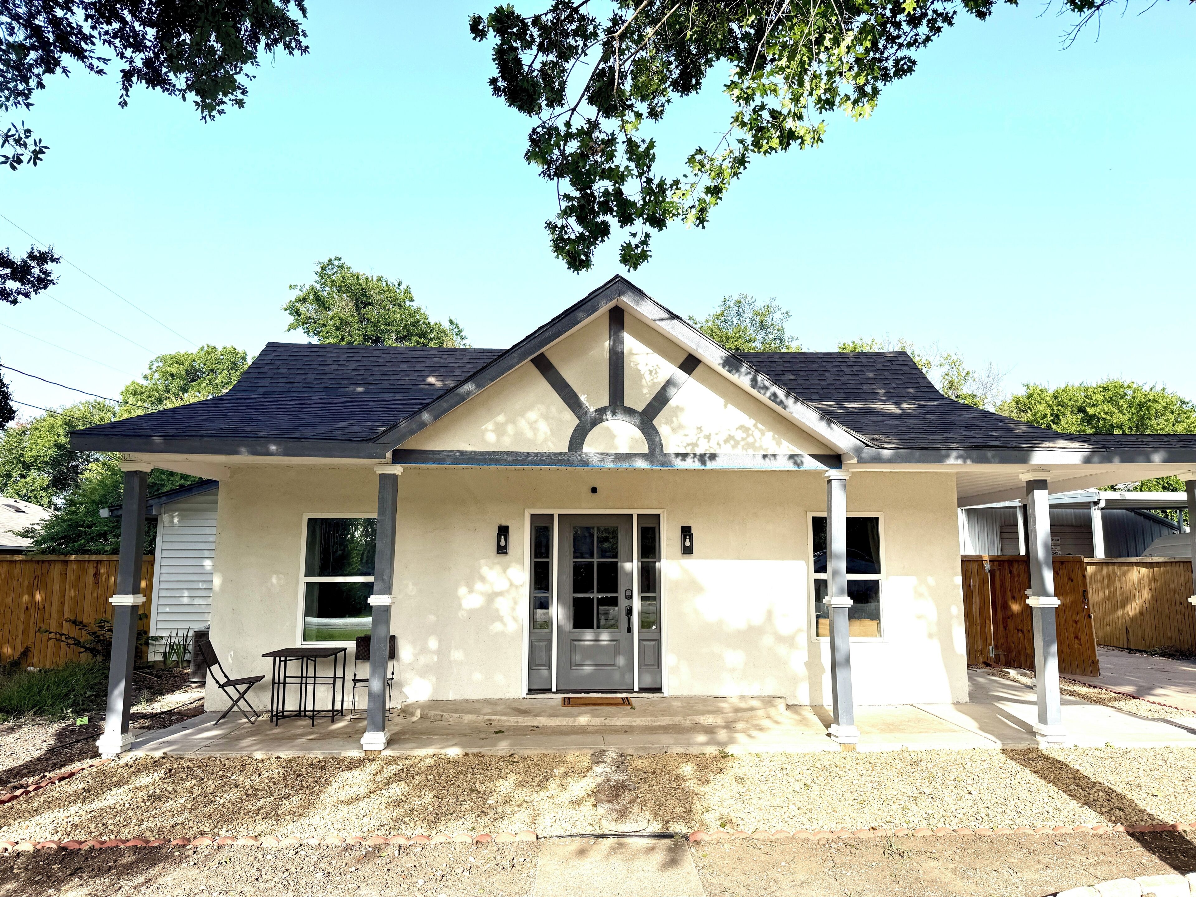 Een gelijkvloers huis met een overdekte veranda, een voordeur en een klein terras.