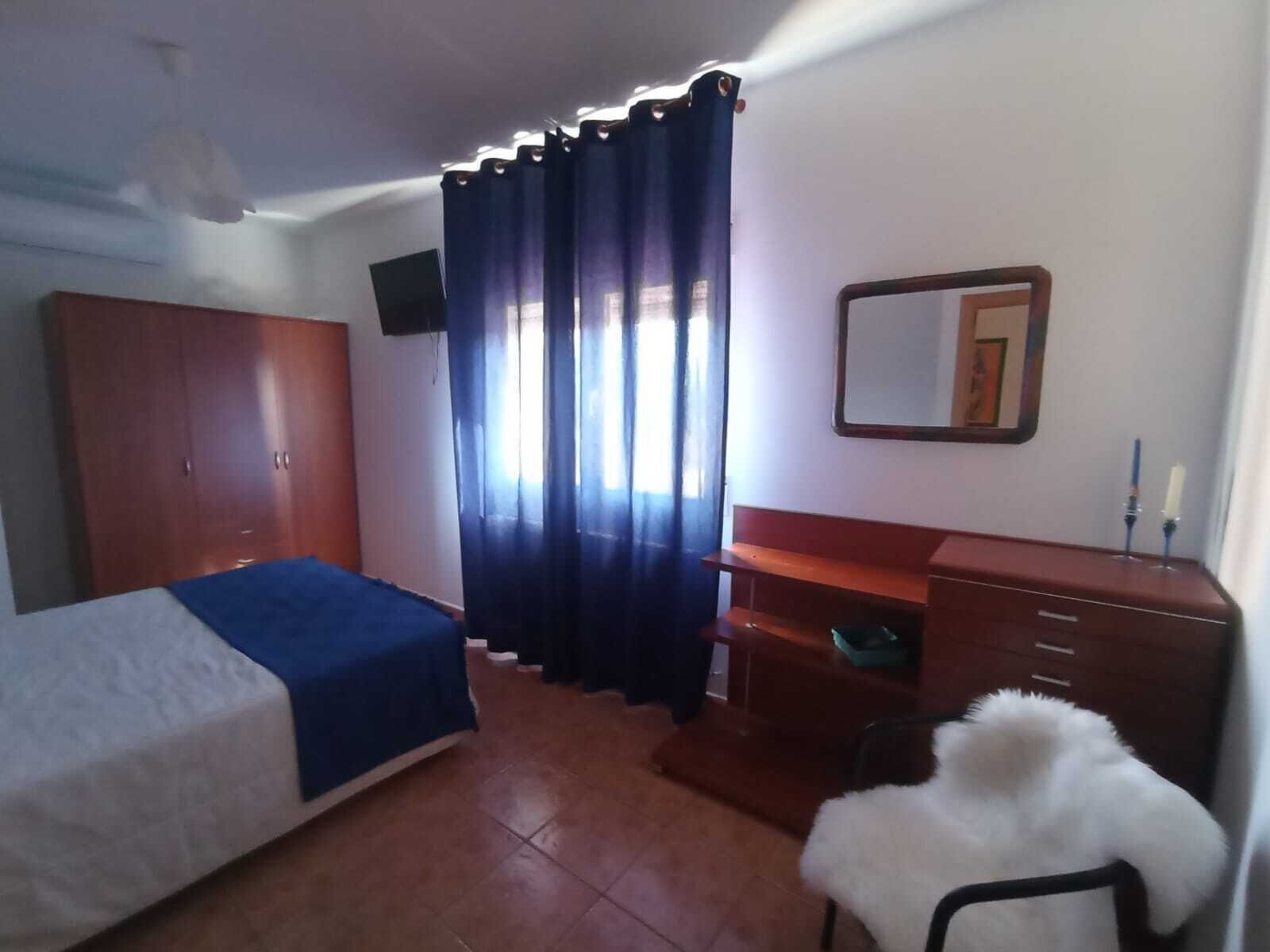 Un dormitorio con cama, cómoda, silla, espejo y armario.