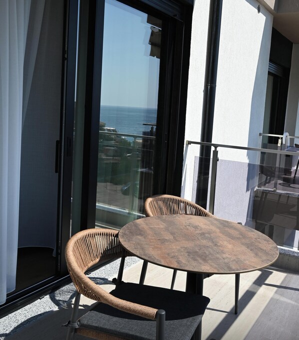 A balcony with a round table and two wicker chairs, overlooking a body of water. - Elmare Hotel  (Himarë)