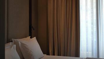A hotel room with a bed, curtains, and a window.