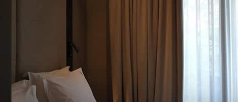 A hotel room with a bed, curtains, and a window.