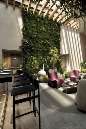 A modern lounge area with a vertical garden wall, seating arrangements, and a dining setup. - Boca Alameda Hotel, Mexico City, Autograph Collection (MEXICO CITY)