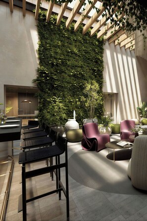 Uma área de lounge moderna com parede de jardim vertical, opções de assento e espaço para refeições.