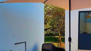 An outdoor seating area with two chairs and a table, a large umbrella, and a door to a building.