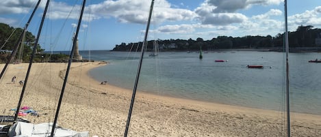 A beach with boats, a sandy shore, and a clear sky.