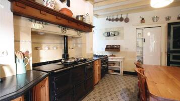 A kitchen with a stove, cabinets, and a dining table.