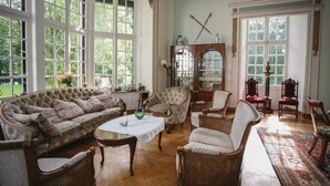 Et traditionelt værelse med sofa, stole, et bord og et skab.