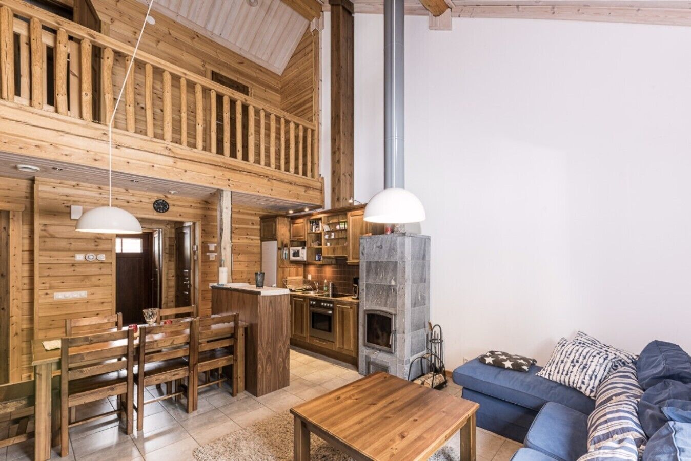 A wooden interior with a dining area, kitchen, and a fireplace.