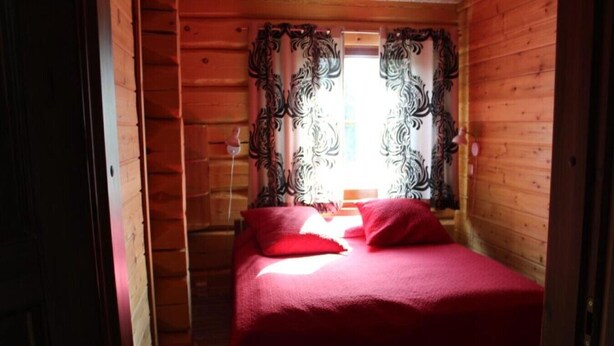 A room with a bed, red bedding, and curtains with a floral pattern. - Lumikkopirtti A | Modern Semi-Detached 3BR Home | Sauna (Ruka)