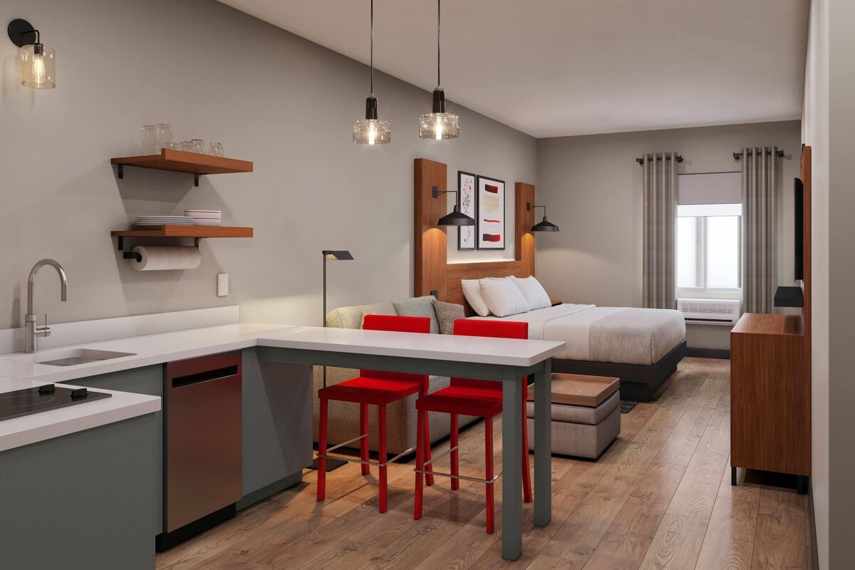 A modern kitchen with a central island, bar stools, and pendant lighting.