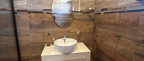 Un bany amb un lavabo blanc, un mirall rodó i un paviment de marbre.