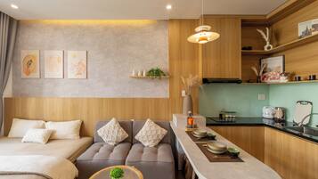 A modern, well-lit room with a sofa, a small dining table, and a kitchen area.