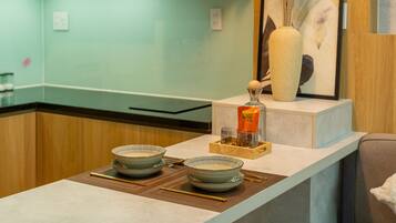 A modern kitchen with wooden cabinets, a light green countertop, and a hanging pendant light.