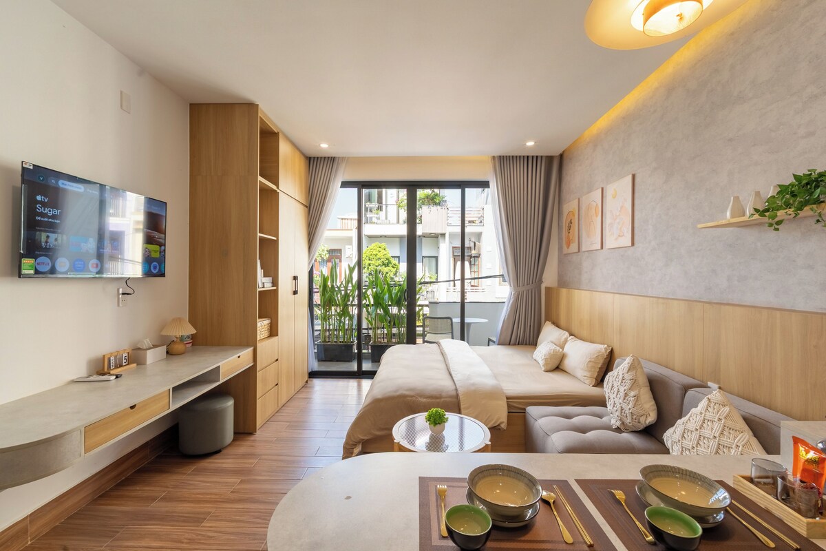 A modern hotel room with a bed, seating area, and a TV on the wall.
