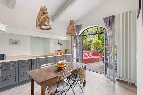 A modern kitchen with grey cabinets, a wooden table, and a bowl of fruit.