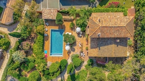 Vista aérea de una propiedad con piscina, mobiliario exterior y exuberante jardinería.