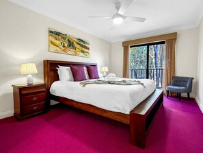 A hotel room with a bed, bedside tables, a chair, a ceiling fan, and a window with curtains. - Villa Magenta - 2-Storey Villa at Cypress Lakes Resort (POKOLBIN)