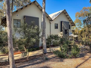 A two-story house with a large garage, surrounded by trees and a landscaped garden. - Villa Magenta - 2-Storey Villa at Cypress Lakes Resort (POKOLBIN)