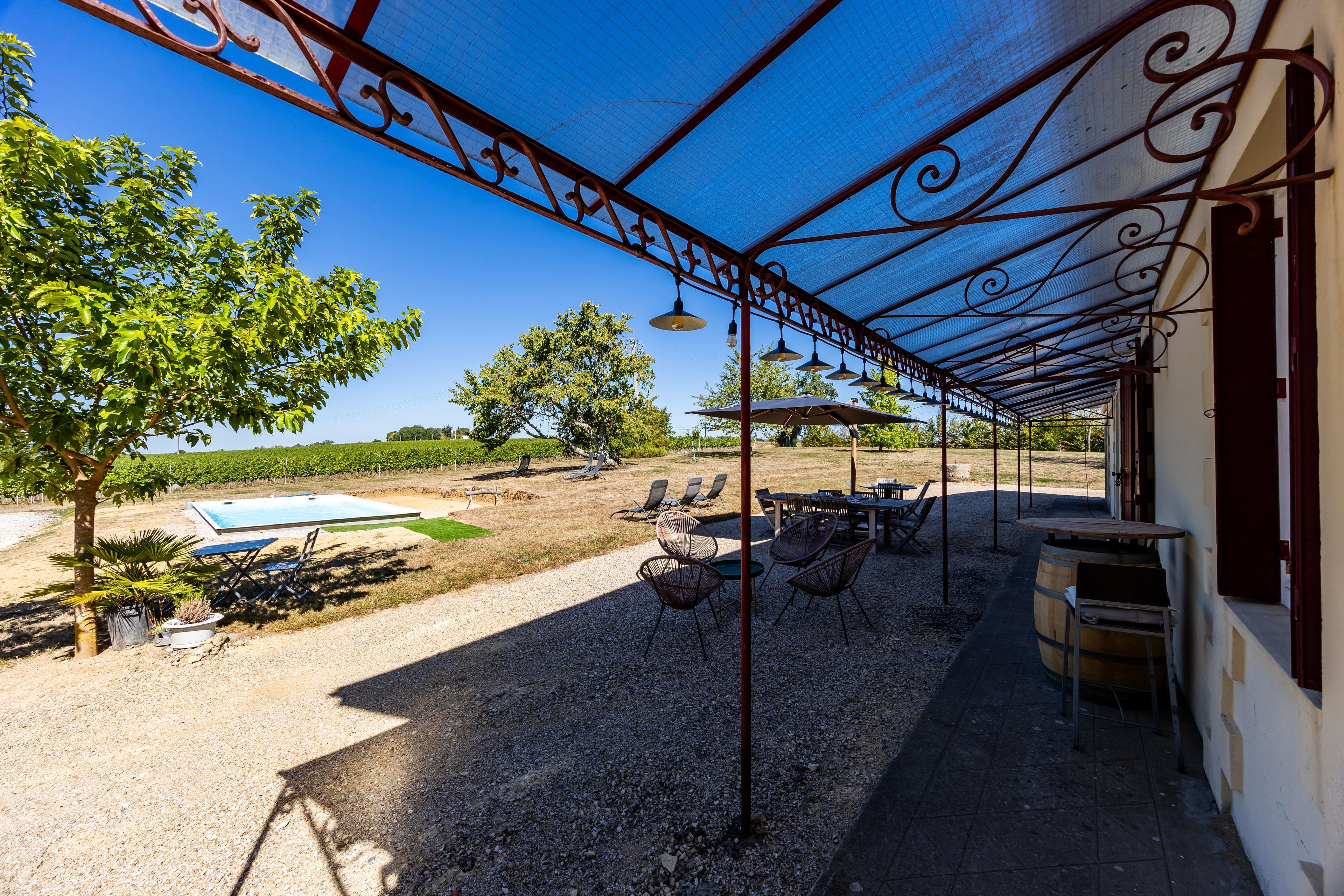 An outdoor patio area with a pergola, seating, and a pool.