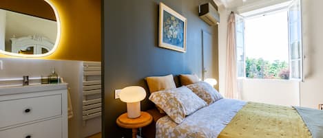 Ein Schlafzimmer mit einem Bett, einem Nachttisch, einer Lampe und einem Bild an der Wand.