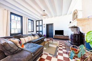Un salon avec un canapé, un téléviseur, un tapis à motifs et un sol à carreaux.