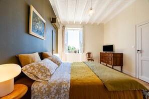Une chambre à coucher avec un lit, une commode, un téléviseur et une fenêtre.