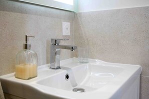Un lavabo de salle de bain avec un distributeur de savon en verre, un robinet et un verre.
