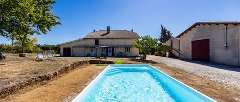 A residential property with a swimming pool, a covered patio, and a garage.