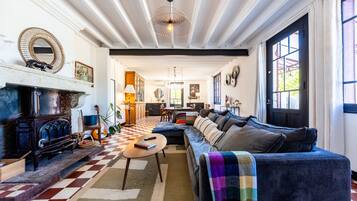 A cozy living room with a checkered floor, a fireplace, a sofa, and a dining area in the background.
