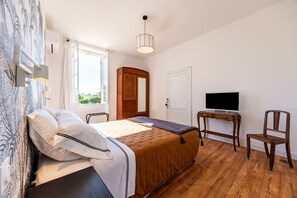 Een slaapkamer met een bed, een bureau met een televisie, een stoel en een kledingkast.