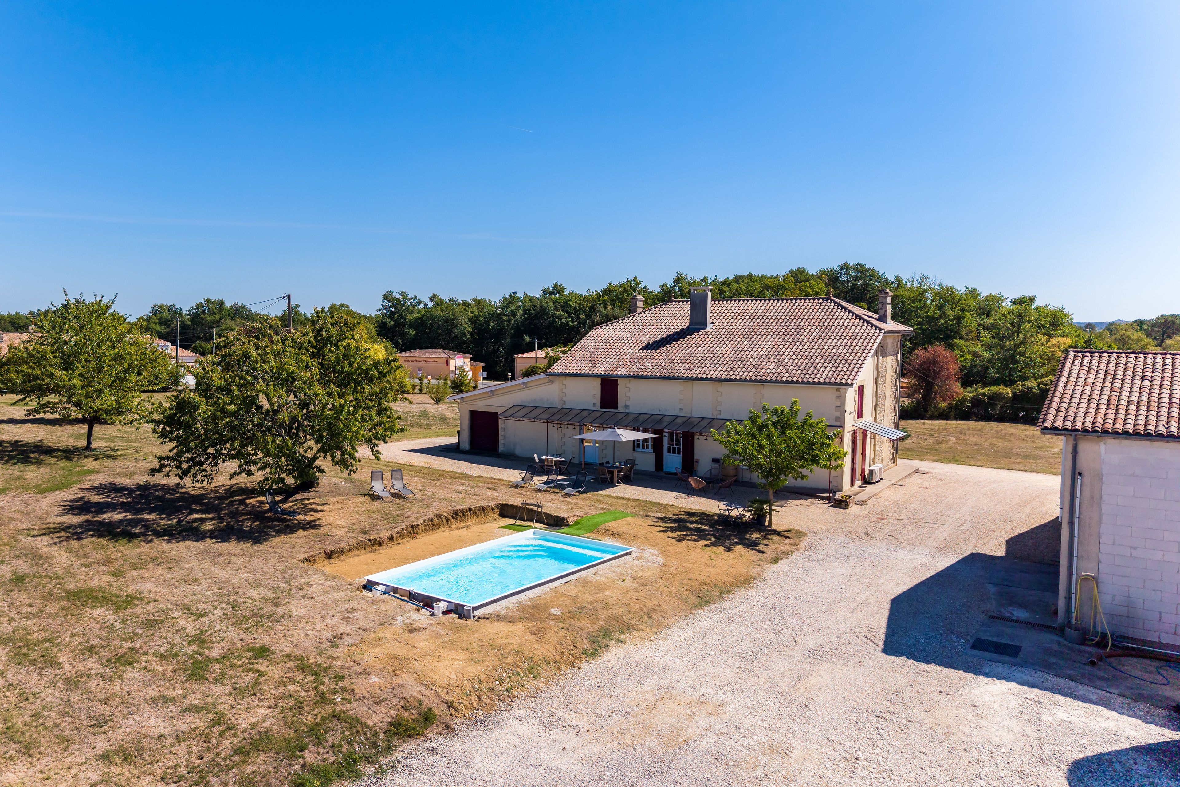 A residential property with a swimming pool, a covered patio, and a detached garage.