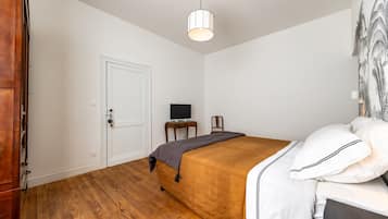 A bedroom with a bed, a desk, a chair, a television, and a wardrobe.