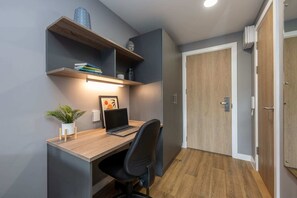 A compact office space with a desk, chair, and shelving unit. - Student Only Luneside (Lancaster)