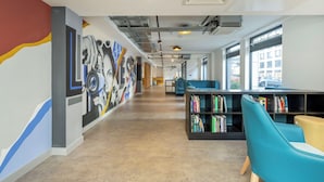 A library interior with bookshelves, seating, and a mural on the wall. - Student Only Luneside (Lancaster)