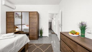 A bedroom with a bed, a wooden wardrobe, a bedside table with a fruit bowl, and a potted plant. - Stunning home in Kakma (Kakma)