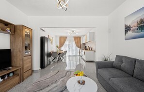 A modern living room with a grey sofa, a coffee table, and a TV on a wooden stand. - Stunning home in Kakma (Kakma)