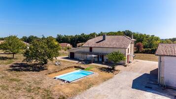 Una propiedad residencial con piscina, terraza cubierta y garaje independiente.