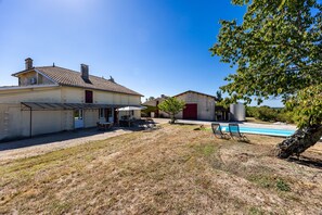 Ein Haus mit einer Terrasse, einem Pool und einem Garten.