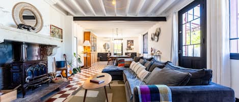 A cozy living room with a checkered floor, a fireplace, a sofa, and a dining area in the background.