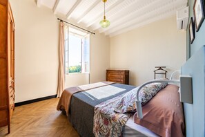 Quarto com cama, cômoda e janela com cortinas.