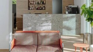Una moderna zona de recepción con mostrador de mármol, un sofá estampado y una pequeña mesa.