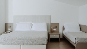 Habitación de hotel con dos camas, una mesita de noche con teléfono y una pequeña mesa con lámpara.