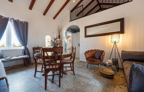 Ein gemütliches Wohnzimmer mit Essbereich, einer Treppe und einem großen Fenster mit Vorhängen.