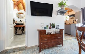 Eine moderne Küche mit Flachbildfernseher über einem Holzkörperschrank, einer Spüle und einem Essbereich mit einem Stuhl.