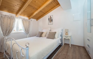 A bedroom with a bed, a nightstand, a dresser, and a ceiling with wooden beams. - Awesome home in Danilo (Danilo)