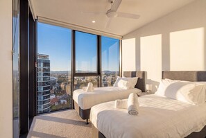 Une chambre d’hôtel avec deux lits, une grande fenêtre et une vue sur la ville.