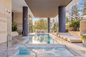 Ein Schwimmbad mit Sonnenterrasse, umgeben von moderner Architektur und Pflanzen.